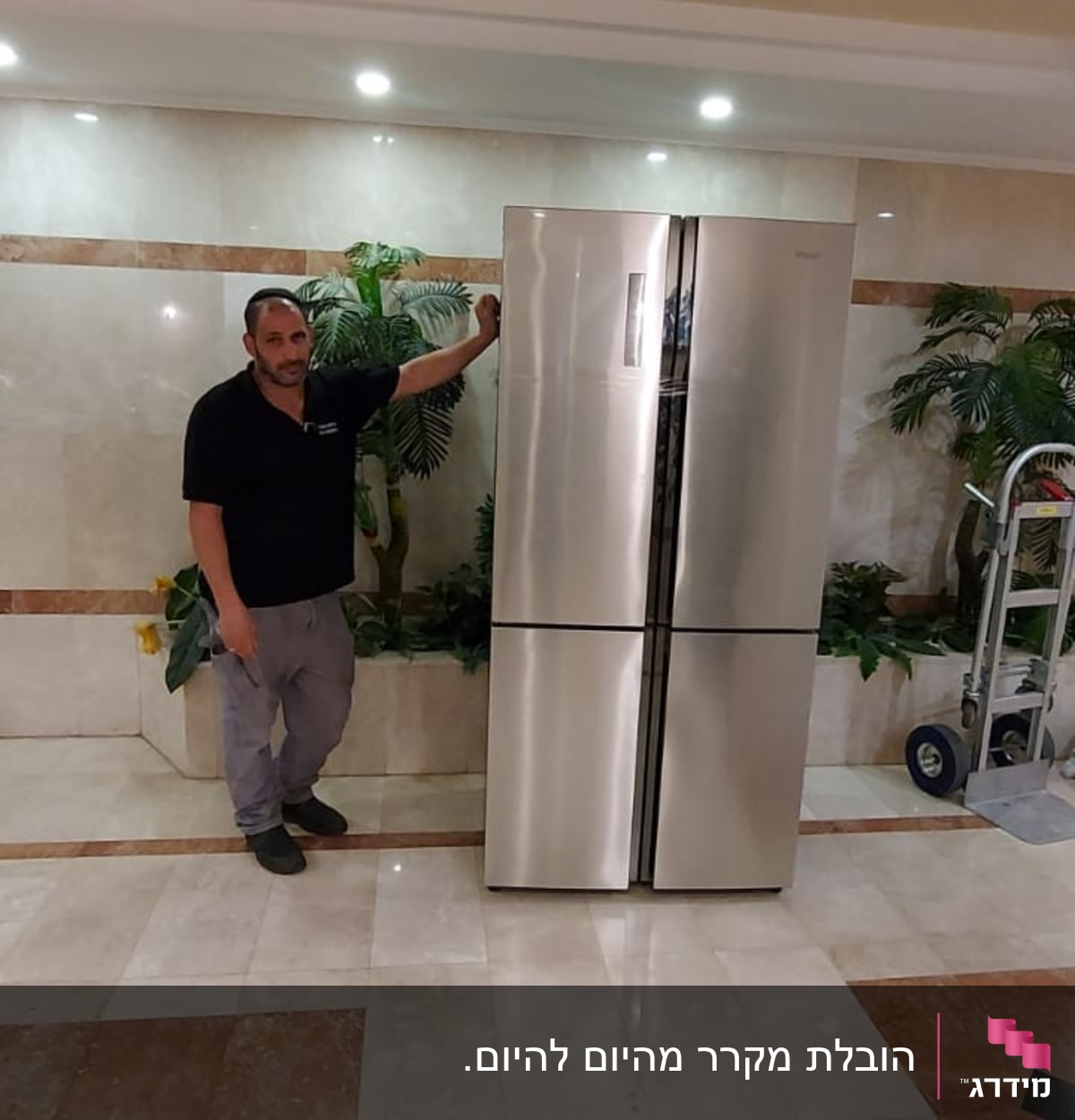 אדם עומד ליד מקרר נירוסטה גדול